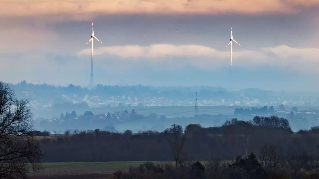 Zwei Windräder ragen aus dem Dunst über der Wetterau heraus. - Bild: Frank Rumpenhorst/dpa
