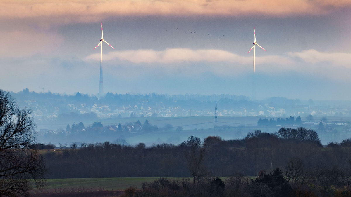 Zwei Windräder ragen aus dem Dunst über der Wetterau heraus. - Foto: Frank Rumpenhorst/dpa