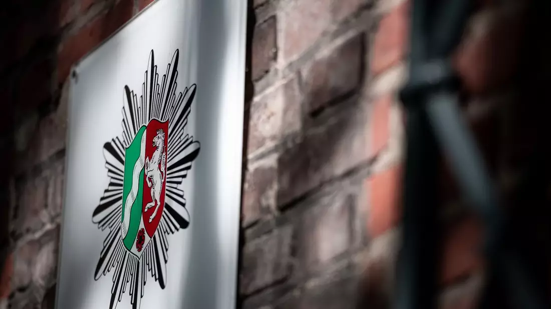 Das Wappen der Polizei Nordrhein-Westfalen hängt an der Wand eines Polizeipräsidiums (Symbolbild). - Bild: Fabian Strauch/dpa