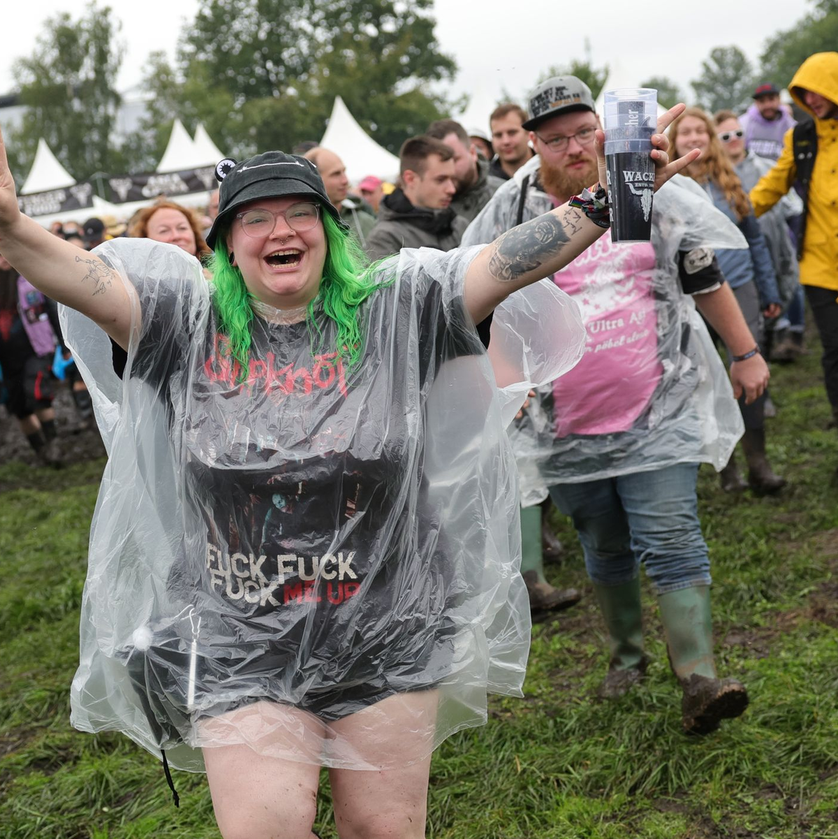 Metal-Fans laufen auf dem nassen Festivalgelände. - Foto: Christian Charisius/dpa