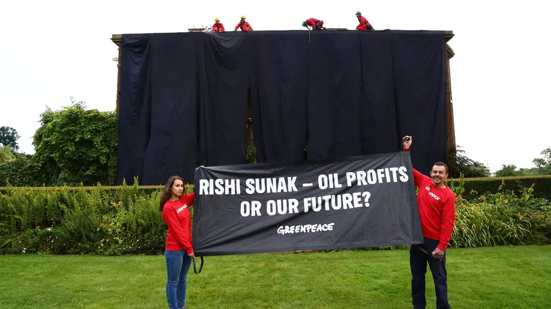 Greenpeace-Aktivisten mit einem Banner vor dem verhüllten Haus des britischen Premiers Rishi Sunak. - Bild: Luca Marino/Greenpeace/PA/dpa