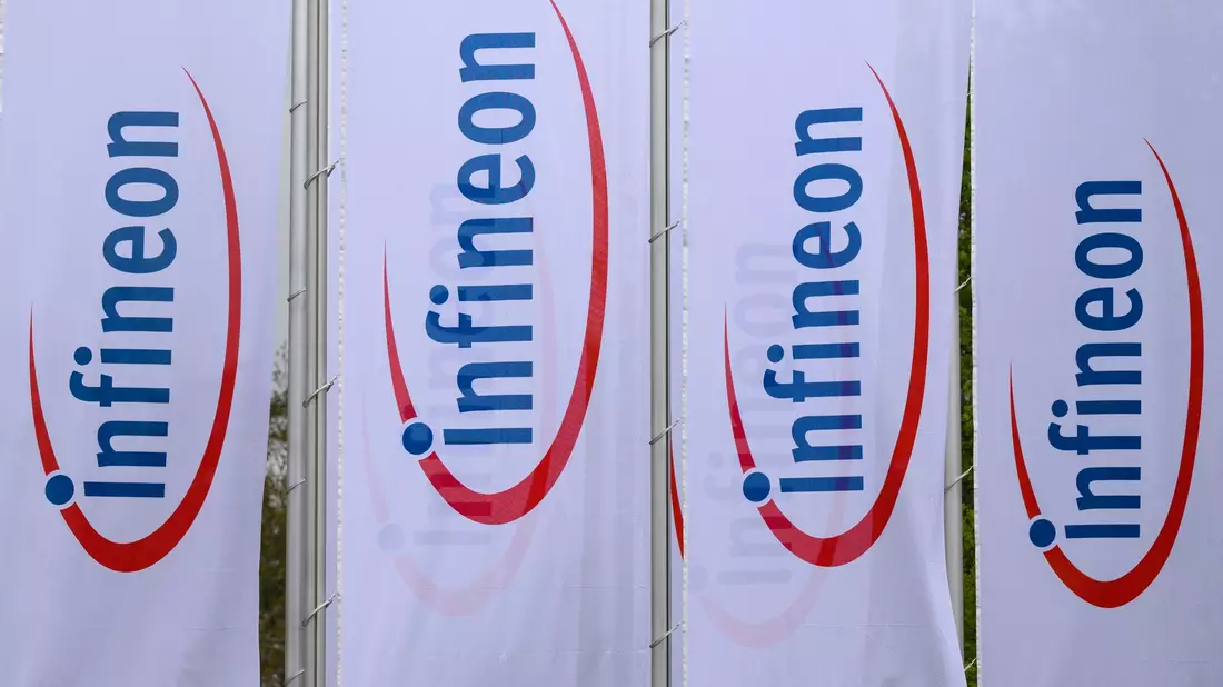 Fahnen mit dem Logo von Infineon wehen vor dem Werk des Chipherstllers in Dresden im Wind. - Bild: Robert Michael/dpa