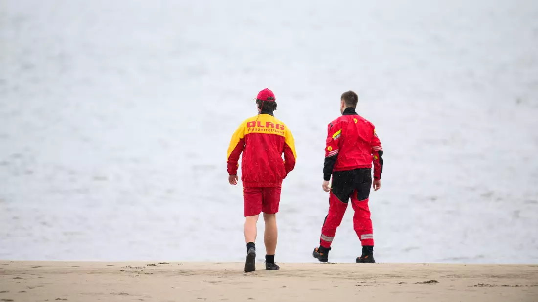 Zwei Mitarbeiter der DLRG an der Elbe. - Bild: Daniel Reinhardt/dpa
