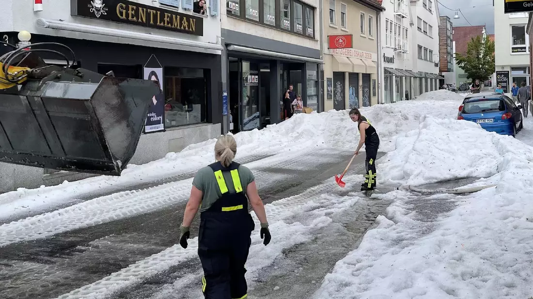 Einsatzkräfte der Feuerwehr räumen Hagel von einer Straße in Reutlingen. - Bild: Schulz/SDMG/dpa