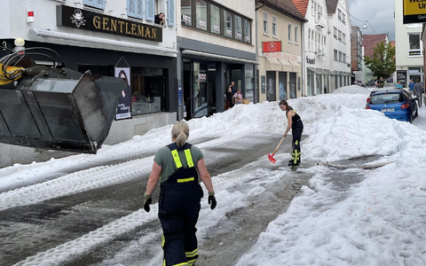 Einsatzkräfte der Feuerwehr räumen Hagel von einer Straße in Reutlingen. - Foto: Schulz/SDMG/dpa