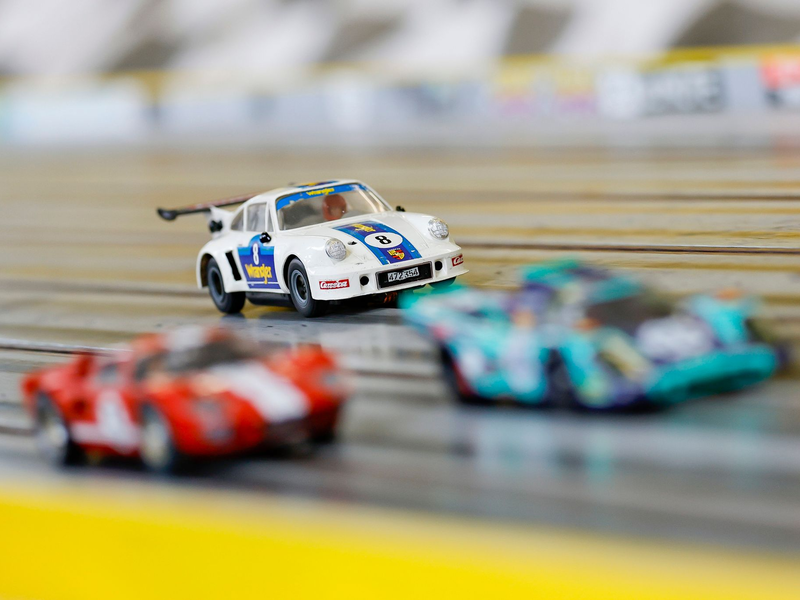 Carrera-Autos fahren auf der Rennstrecke im Rennbahn-Center Franken im bayerischen Heroldsberg. - Foto: Daniel Löb/dpa