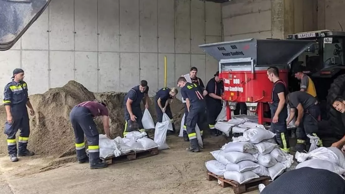 Mitarbeiter der Feuerwehr befüllen in Deutschlandsberg (Steiermark) Sandsäcke im Kampf gegen die Überflutungen in der Gegend. - Bild: -/BFVMZ/APA/dpa