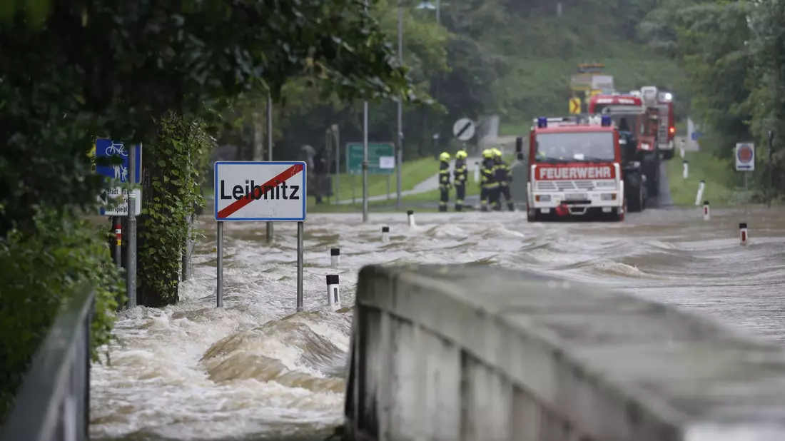 Feuerwehrwagen stehen vor einer überfluteten Brücke über die Sulm am Ortsausgang von Leibnitz in der Steiermark. - Bild: Erwin Scheriau/APA/dpa