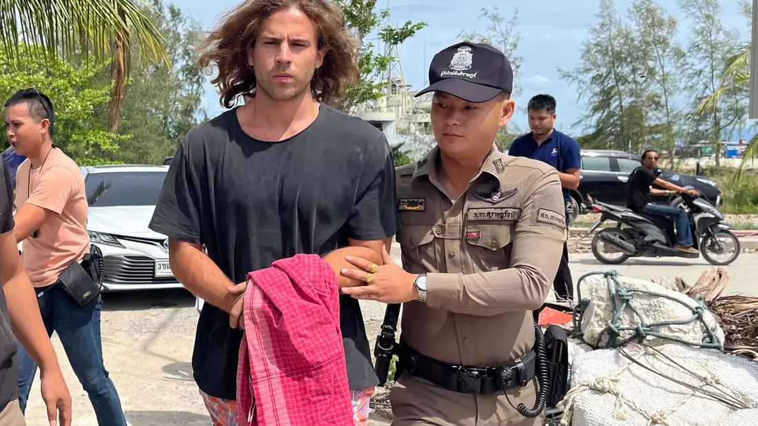 Ein thailändischer Polizist (r.) eskortiert einen Spanier, der unter Verdacht steht, einen  Chirurgen ermordet  zu haben. - Bild: Somkeat Ruksaman/AP/dpa