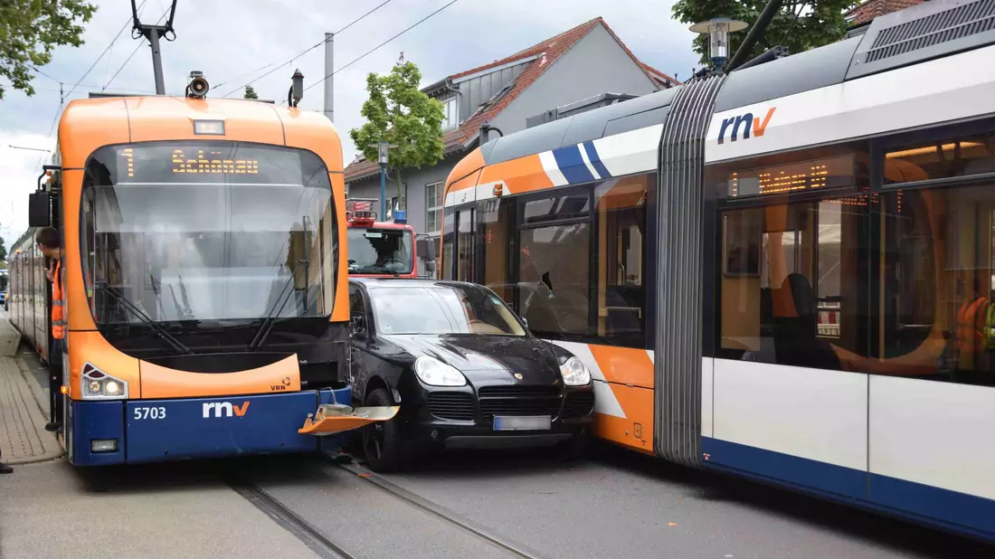 Ein Porsche ist nach einem leichtsinnigen Überholmanöver zwischen zwei Straßenbahnen eingeklemmt. - Bild: Priebe/pr-video/dpa