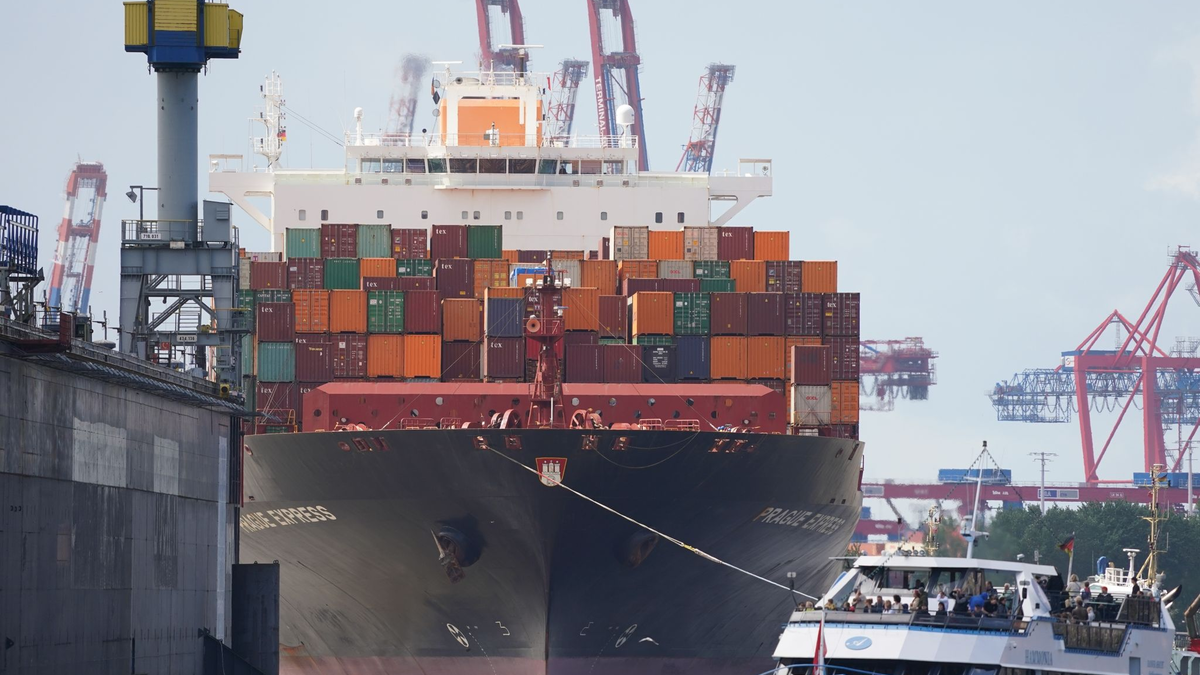 Das Containerschiff «Prague Express» der Reederei Hapag-Lloyd wird von Schleppern an einen Containerterminal im Hafen gezogen. - Foto: Marcus Brandt/dpa