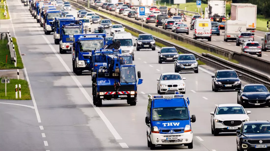 Fahrzeuge verschiedener bayerischer Ortsverbände des THW fahren mit Materialien zum Brückenbau über die Autobahn 8 in Richtung Slowenien. - Bild: Matthias Balk/dpa