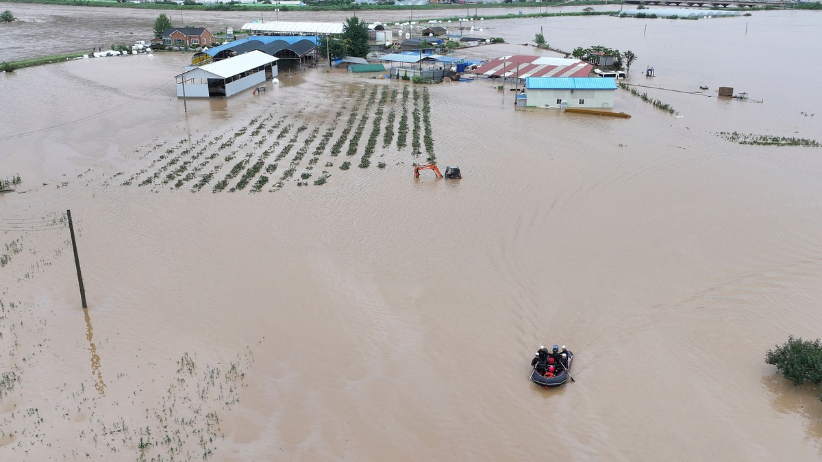 Rettungskräfte suchen auf einem Boot nach vermissten Personen im Hochwasser, nachdem der Tropensturm «Khanun» auf Land getroffen ist. - Foto: Yun Kwan-shick/Yonhap/AP/dpa