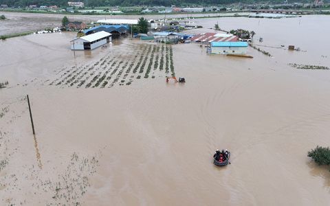 Rettungskräfte suchen auf einem Boot nach vermissten Personen im Hochwasser, nachdem der Tropensturm «Khanun» auf Land getroffen ist. - Foto: Yun Kwan-shick/Yonhap/AP/dpa