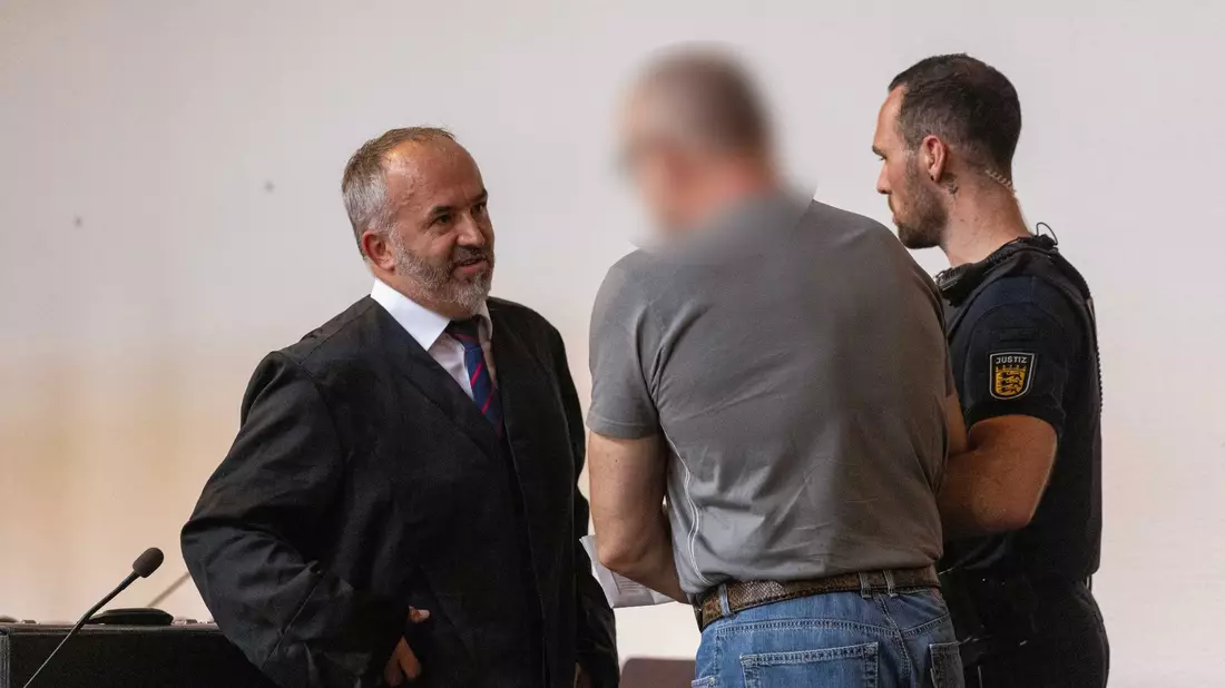 Der Angeklagte (M) spricht mit seinem Verteidiger (l) im Gericht. - Bild: Philipp von Ditfurth/dpa