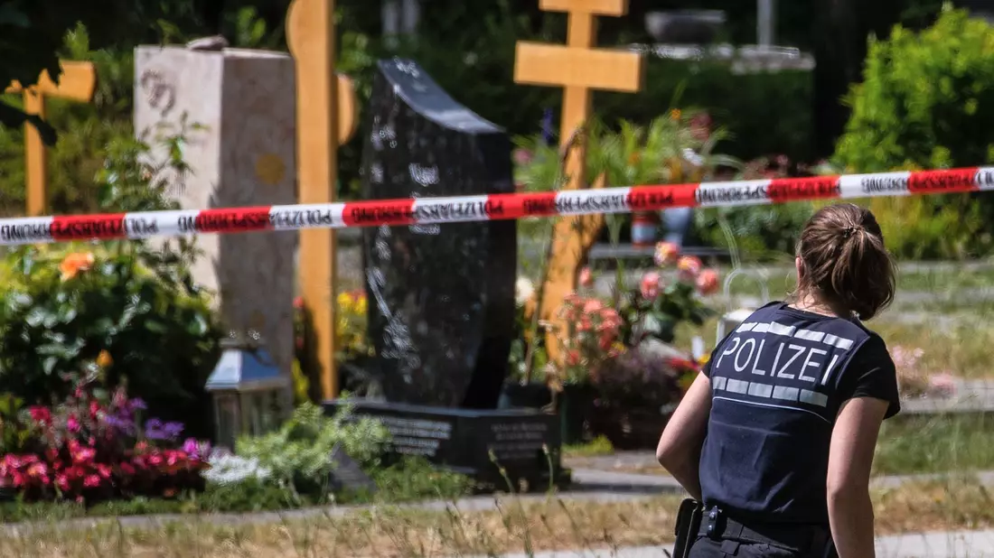 Eine Polizistin geht über den abgesperrten Teil eines Friedhofs in Altbach, wo im Juni eine Handgranate auf eine Trauergemeinde geworfen wurde. - Bild: Christoph Schmidt/dpa