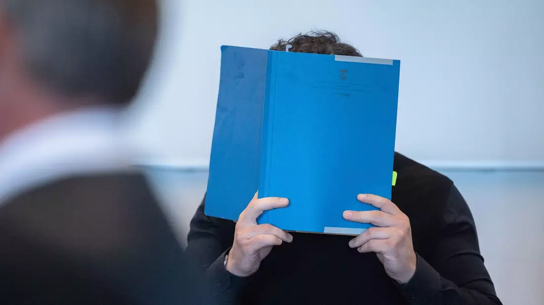 Einer der Hauptangeklagten versteckt zu Beginn des Prozess wegen Betrugs mit Corona-Tests sein Gesicht. - Bild: Rolf Vennenbernd/dpa