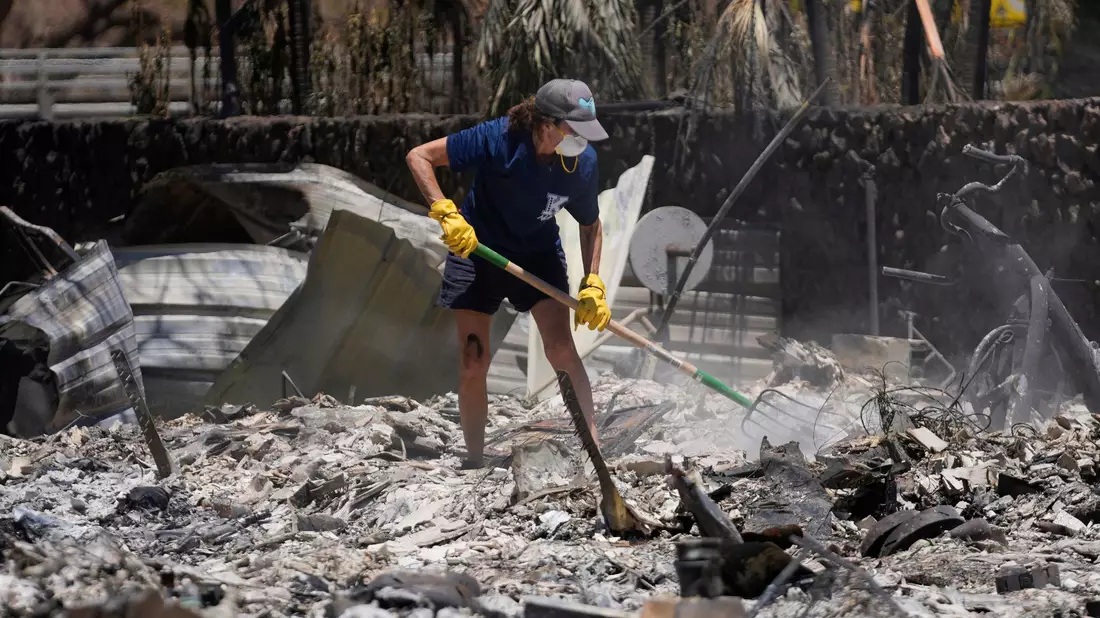 Eine Frau gräbt in Lahaina auf Hawaii in den Trümmern eines zerstörten Hauses. - Bild: Rick Bowmer/AP/dpa