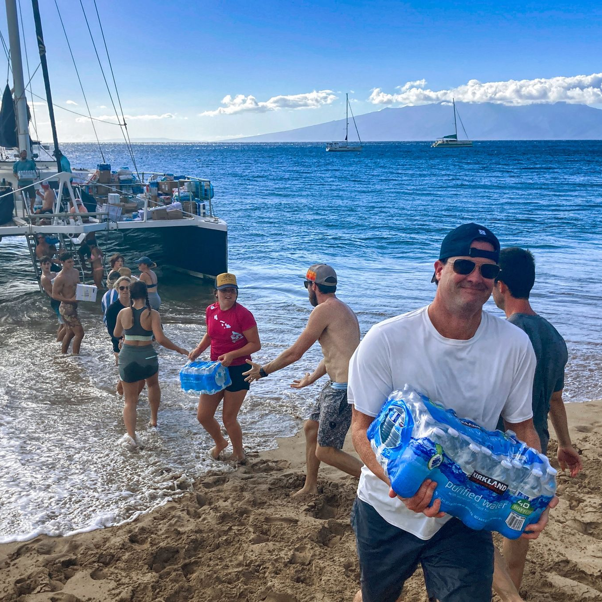 Freiwillige aus Maalaea Bay auf Maui entladen Spenden von einem Boot. - Foto: Rick Bowmer/AP/dpa