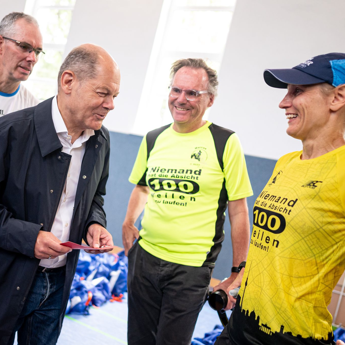 Entspannter Besuch: Scholz unterhält sich mit Läuferinnen und Läufern beim Berliner Mauerweglauf. - Foto: Fabian Sommer/dpa
