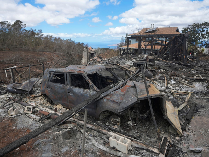 Die verkohlten Überreste eines Fahrzeugs stehen  in Kula neben einem von einem Waldbrand zerstörten Haus. - Foto: Rick Bowmer/AP
