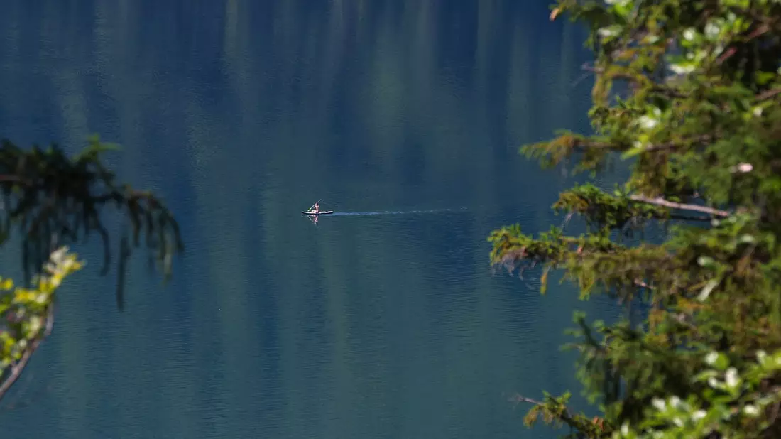 Sommer-Feeling in Südbayern: Ein Mann paddelt auf einem Surfboard über den türkisfarbenen Alpsee. - Bild: Karl-Josef Hildenbrand/dpa