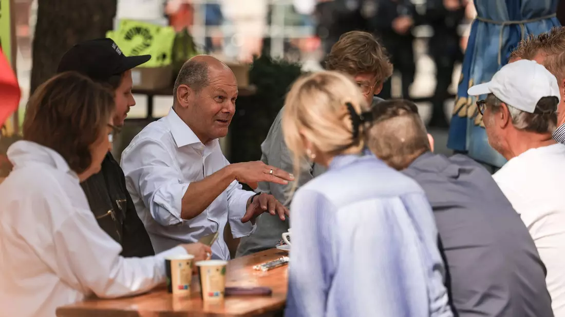 Bundeskanzler Olaf Scholz (M, SPD) spricht vor einem Büdchen mit Düsseldorfer Bürgern. - Bild: Oliver Berg/dpa
