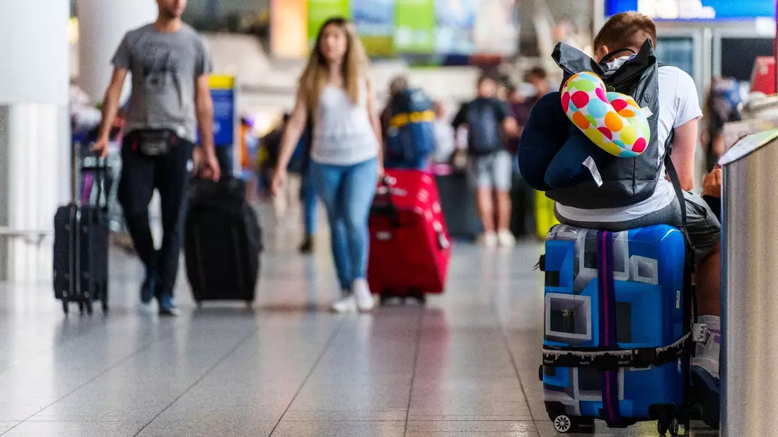 Ein junger Mann ruht sich auf seinem Koffer im Frankfurter Flughafen aus. - Bild: Andreas Arnold/dpa