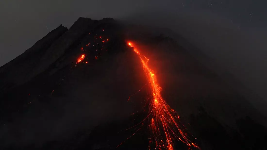 Der orange-rote Lavastrom leuchtet in der Dunkelheit. - Bild: Angga Budhiyanto/ZUMA Press Wire/dpa