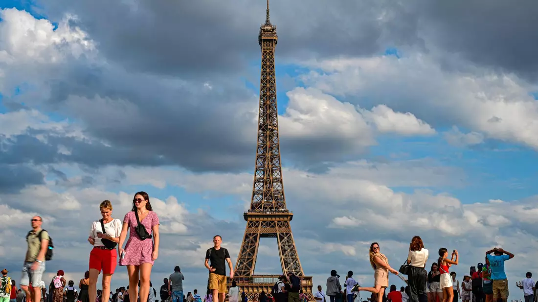 Touristen am Eiffelturm, dem Wahrzeichen der Stadt. Ein Mann ist nach einem Fallschirm-Sprung vom Eiffelturm festgenommen worden. - Bild: Miguel Medina/AFP/dpa