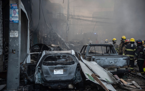 Feuerwehrleute arbeiten neben zerstörten Fahrzeugen nach einer starken Explosion, die ein Marktviertel mit vielen Geschäften erschüttert hat. - Foto: Jolivel Brito/AP/dpa