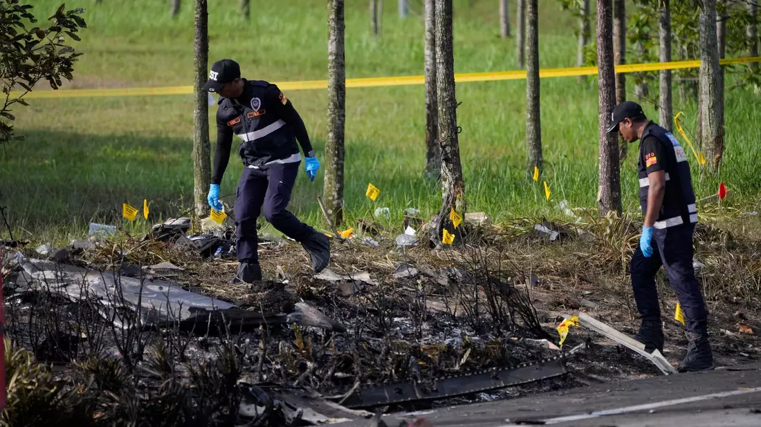 Polizisten ermittelt an der Absturzstelle des Kleinflugzeugs in Malaysia. - Bild: Vincent Thian/AP