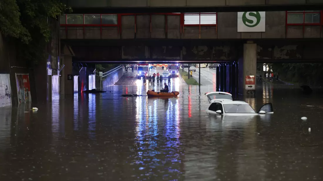 Einsatzkräfte der Feuerwehr können nur noch mit einem Schlauchboot zu den Autos in einer überschwemmten Unterführung gelangen. - Bild: Oßwald/News5 /dpa