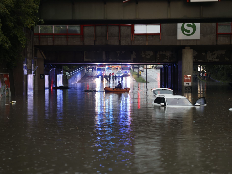 Einsatzkräfte der Feuerwehr können nur noch mit einem Schlauchboot zu den Autos in einer überschwemmten Unterführung gelangen. - Foto: Oßwald/News5 /dpa