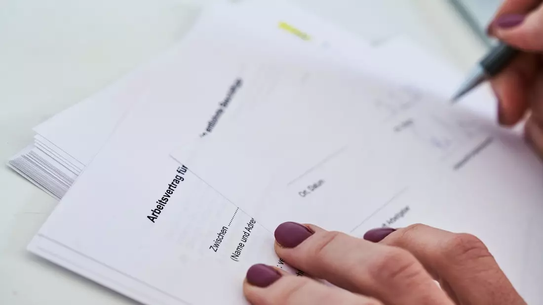 Eine Frau unterschreibt einen Arbeitsvertrag. - Bild: Annette Riedl/dpa