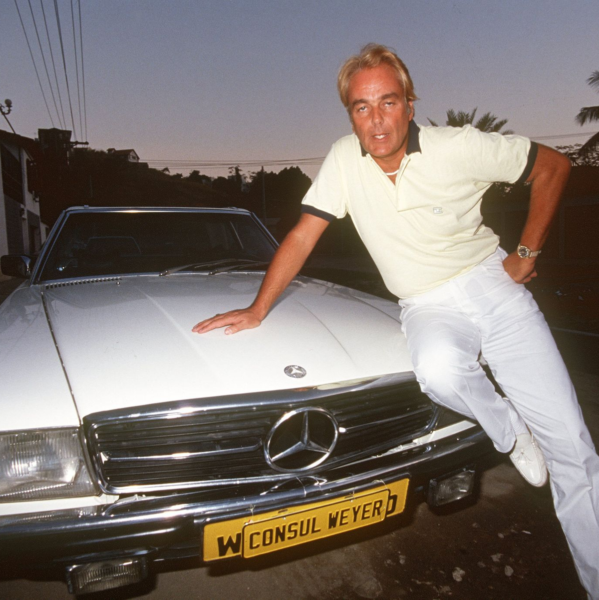 Hans-Hermann Weyer, bekannt durch den Verkauf von Titeln und Adelsprädikaten,  posiert auf seinem Wagen (1985). - Foto: Istvan Bajzat/dpa