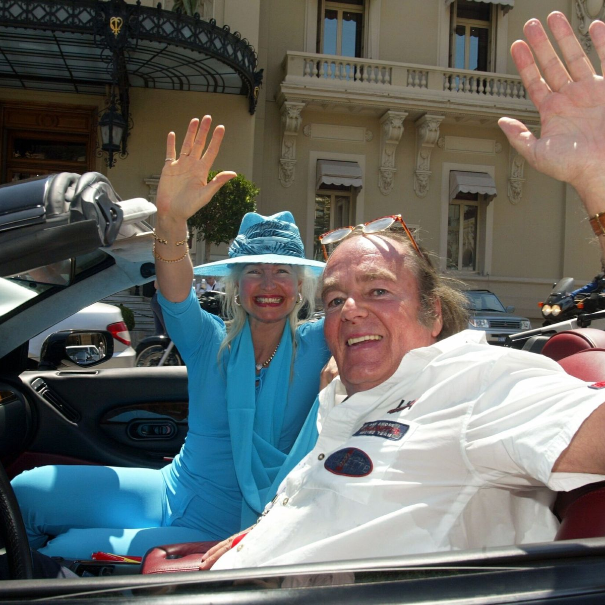 Hans-Hermann Weyer und seine Ehefrau Christina winken aus ihrem Aston Martin-Cabriolet (2002). - Foto: Gero Breloer/dpa