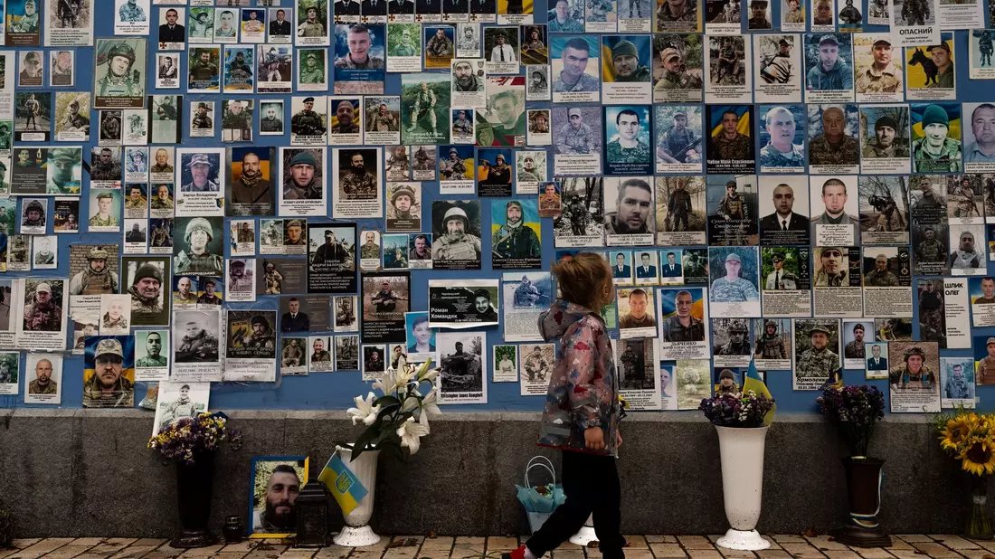 Ein Mädchen betrachtet Fotos von ukrainischen Soldaten, die im Krieg gegen Russland gefallen sind. - Bild: Jae C. Hong/AP/dpa