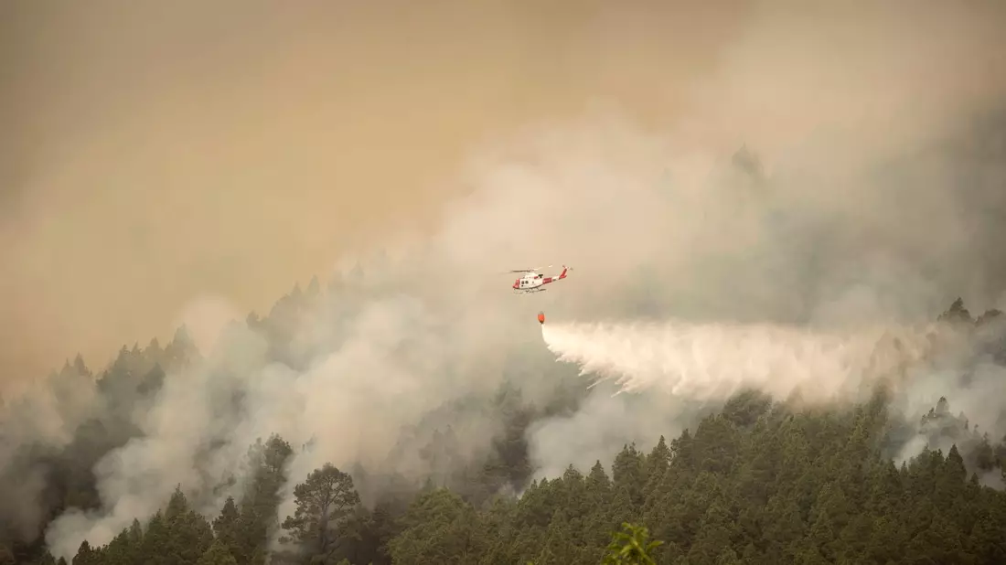 Ein Hubschrauber überfliegt einen Brand am Stadtrand von El Rosario während eines Löscheinsatzes. - Bild: Arturo Rodriguez/AP