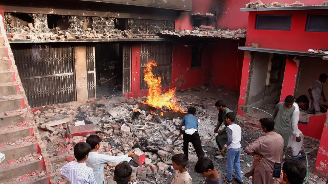 Jugendliche stehen in Jaranwala vor einer Kirche, die beschädigt und niedergebrannt wurde. - Bild: Muhammad Shafqat/AP/dpa