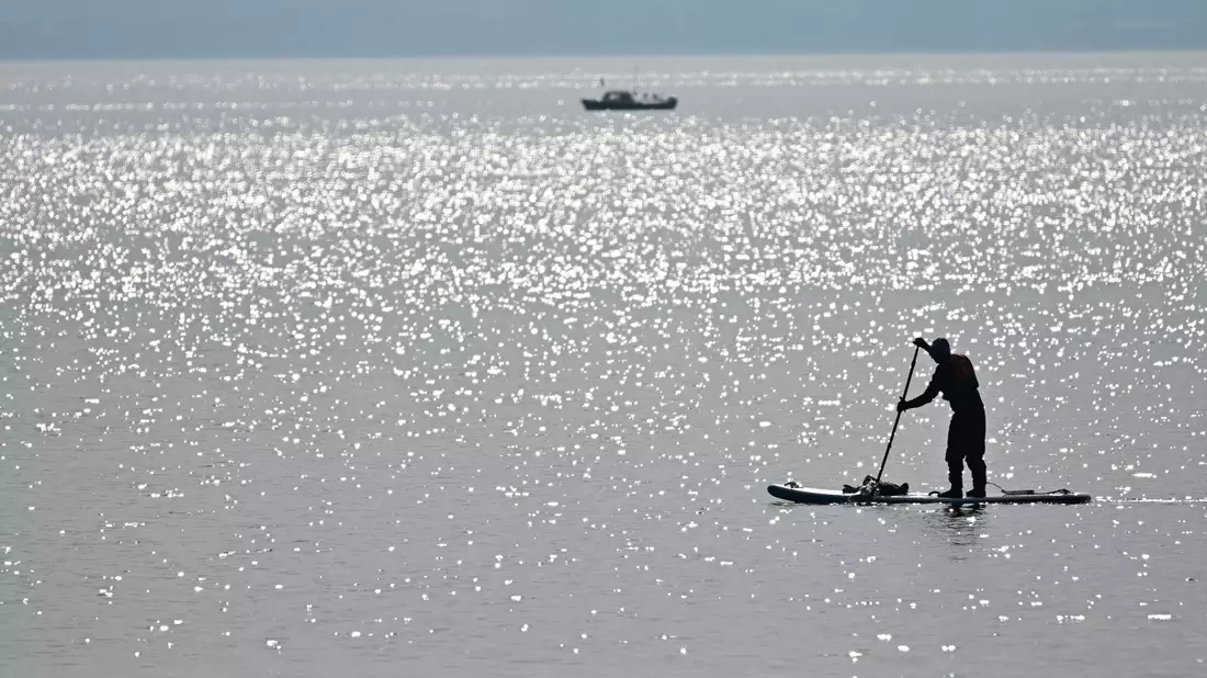 Ein Stand-up-Paddler paddelt über den Bodensee. (Symbolbild) - Bild: Felix Kästle/dpa