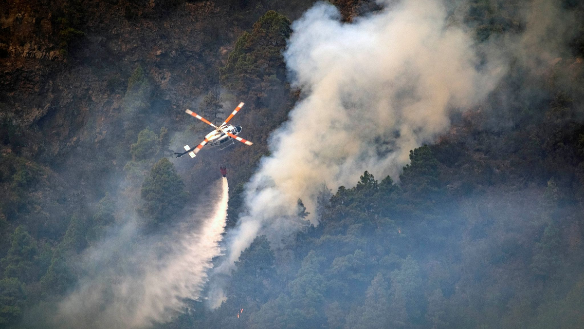 Ein Hubschrauber wirft Wasser auf die Flammen, während sich das Feuer durch den Wald in Richtung der Stadt Pinolere ausbreitet. - Foto: Arturo Rodriguez/AP/dpa