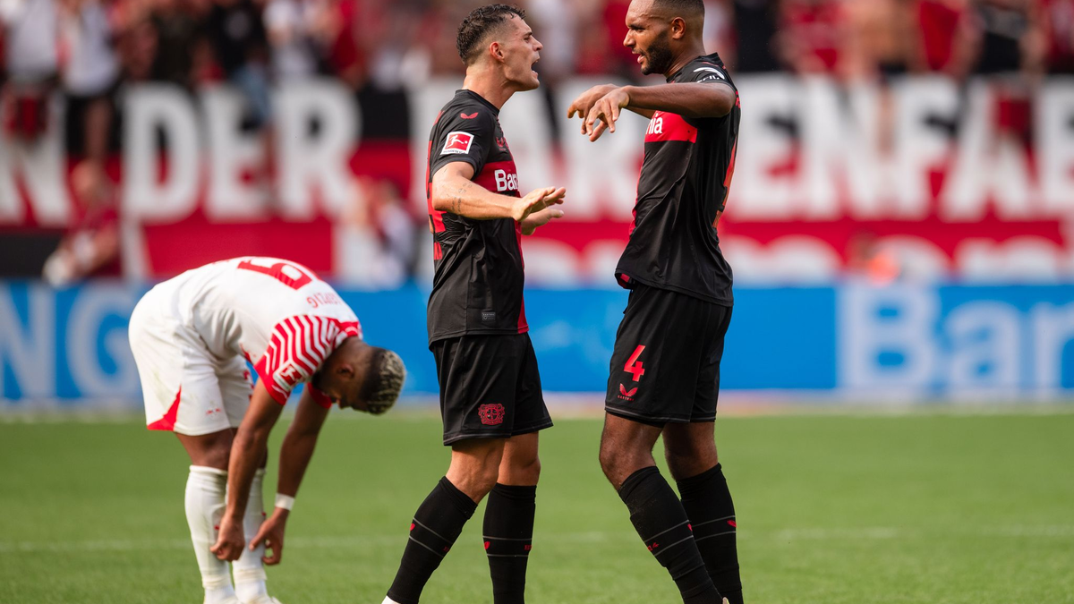 Leverkusens Granit Xhaka (M) und Jonathan Tah klatschen sich nach der Partie ab. Links Leipzigs Benjamin Henrichs. - Foto: Marius Becker/dpa