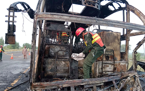 Rettungskräfte untersuchen den verbrannten Bus an der Unfallstelle auf einer Autobahn. - Foto: Uncredited/Rescue 1122 Emergency Department/AP/dpa