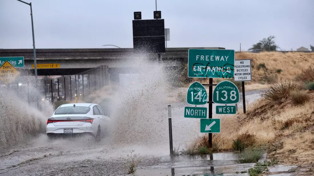 Ein Fahrzeug fährt durch eine überflutete Autobahnauffahrt nahe der kalifornischen Stadt Palmdale. - Bild: Richard Vogel/AP