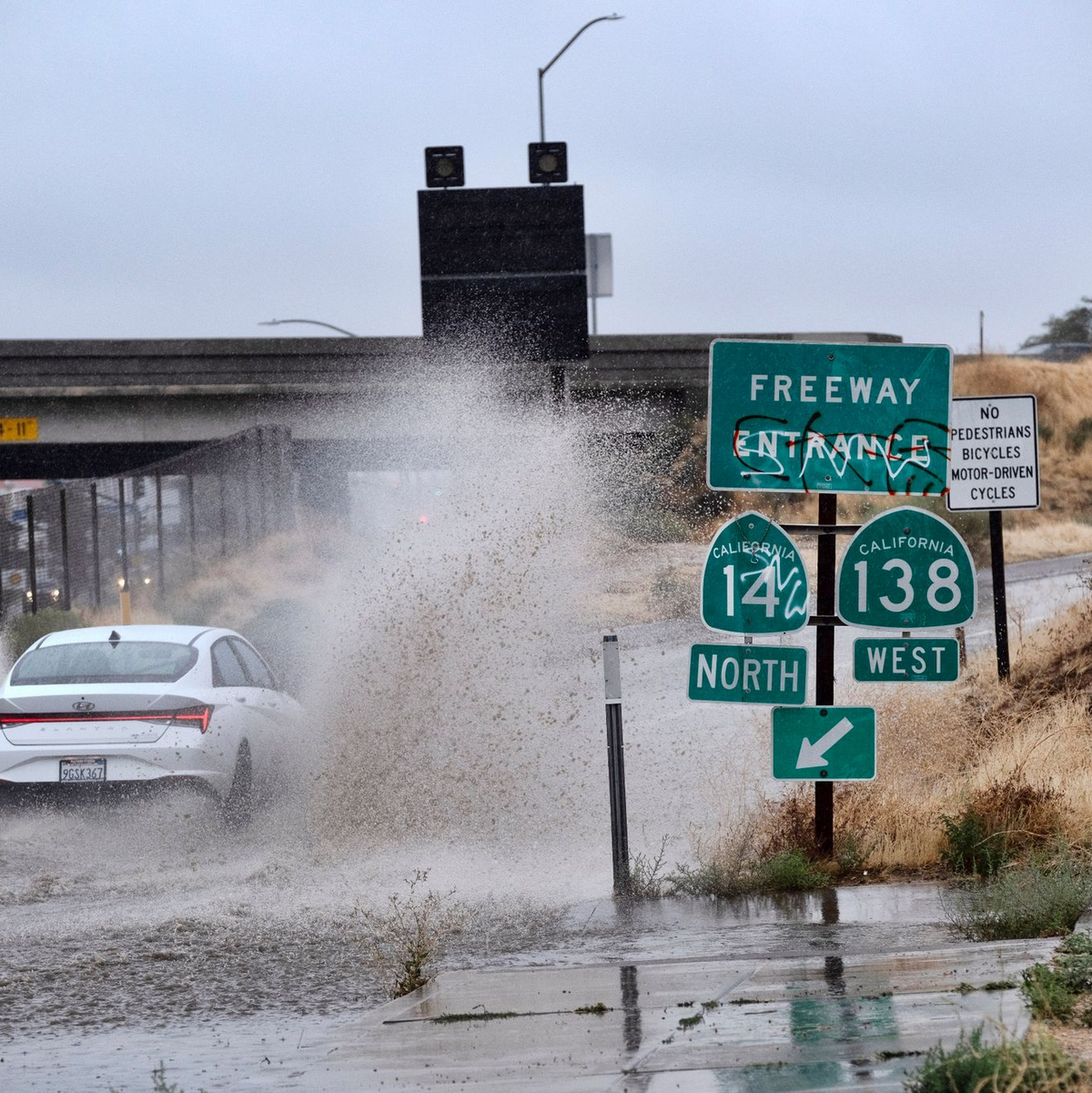Ein Fahrzeug fährt durch eine überflutete Autobahnauffahrt nahe der kalifornischen Stadt Palmdale. - Foto: Richard Vogel/AP