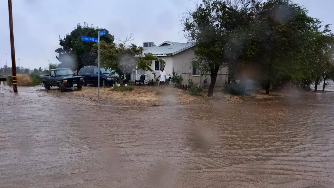 Ein Anwohner prüft während eines Regengusses in Palmdale die Überschwemmungen rund um sein Haus. - Bild: Richard Vogel/AP