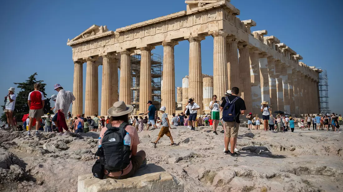 Touristen an einem heißen Tag bei ihrem Besuch des Parthenon-Tempels auf dem Akropolis-Hügel in Athen. - Bild: Angelos Tzortzinis/dpa