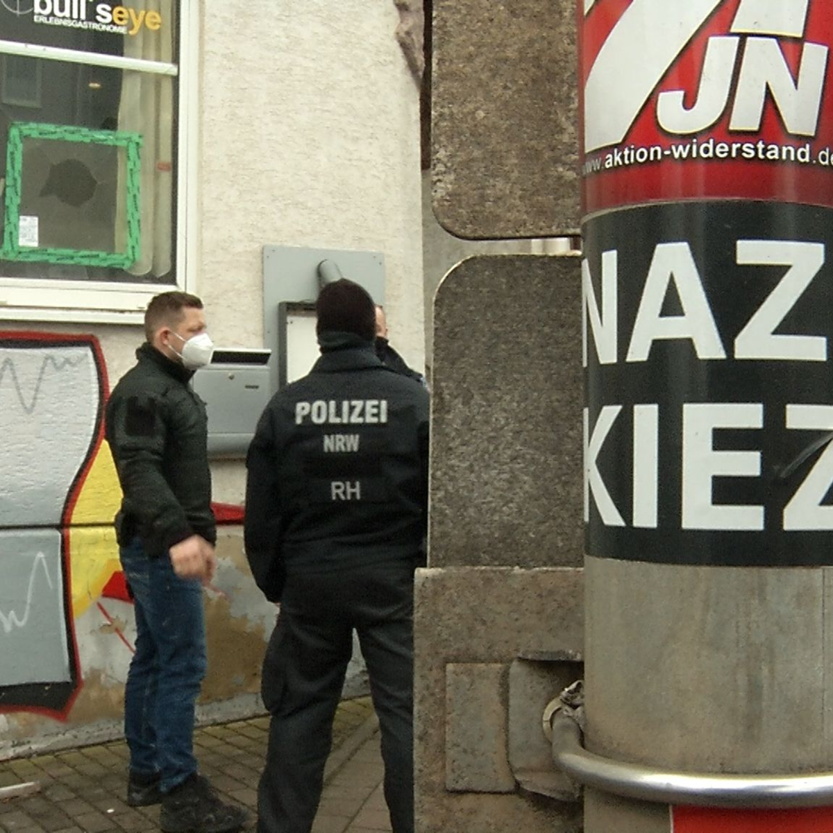 Polizisten stehen vor der Gaststätte «Bull's Eye». An einem Pfahl ist ein Aufkleber mit der Aufschrift «Nazi Kiez» zu sehen. - Foto: Martin Wichmann TV/dpa