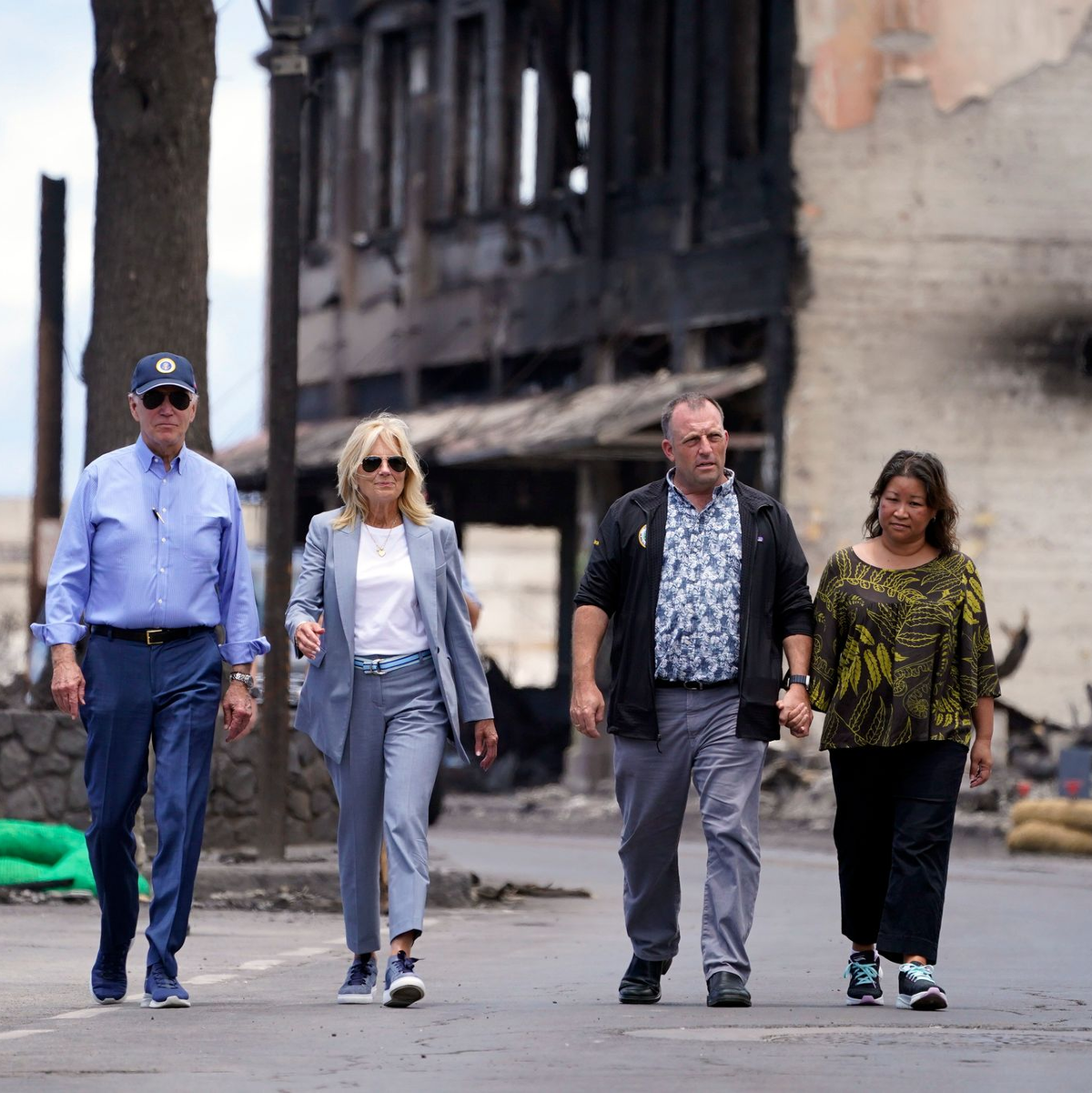 US-Präsident Joe Biden (l) und First Lady Jill Biden (2.v.l) gehen zusammen mit Josh Green, Gouverneur von Hawaii, und seiner Frau Jaime Green durch ein von Waldbränden auf der Insel Maui verwüstetes Gebiet. - Foto: Evan Vucci/AP